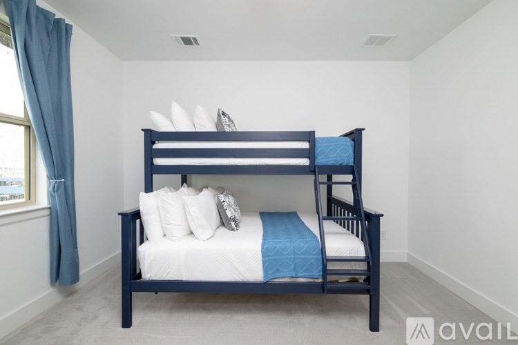 A bed with a blue blanket and white pillows in a room with a window.