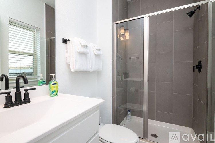 A white sink with a black faucet and a bottle of hand soap on it.