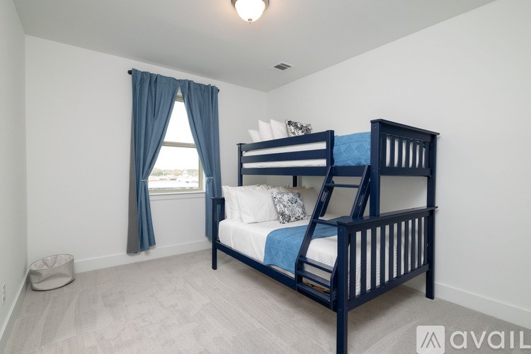 A bedroom with a bunk bed and a window with curtains.