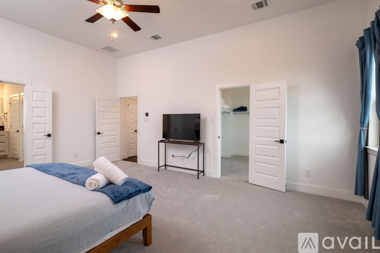 A bedroom with a bed, a television, and a ceiling fan.