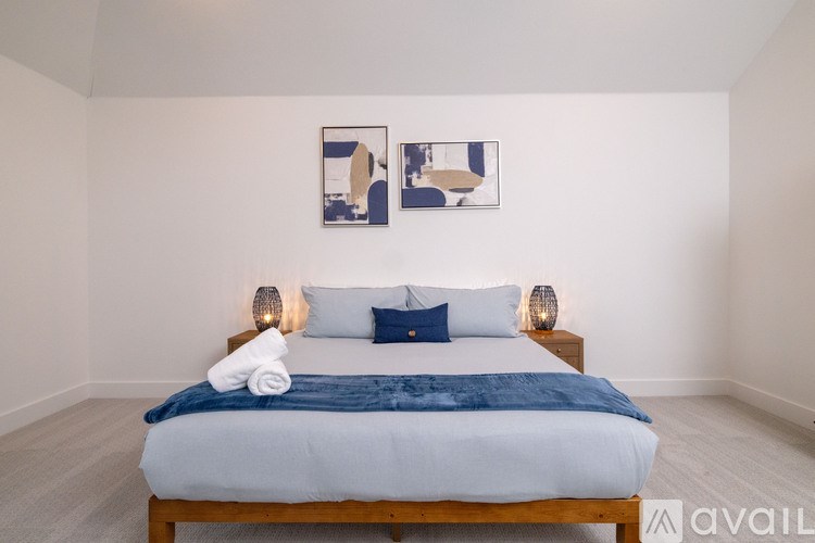 A bedroom with a bed, two lamps, and two pictures on the wall.