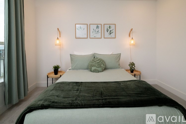 A bedroom with a large bed and two small tables with plants on them.