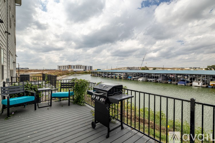 A balcony with a grill and chairs overlooking a body of water.