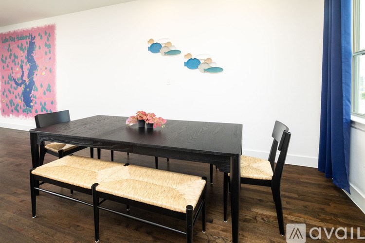 A black dining table with a bench and a vase of flowers on it.