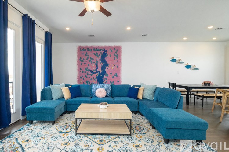 A living room with a blue couch and a painting of Lake Ray Hubbard.