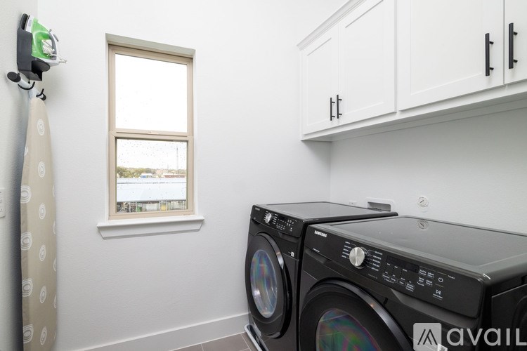 A washing machine is in a room with a window and a curtain.