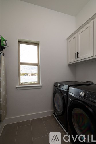A washing machine is in a laundry room with a window.