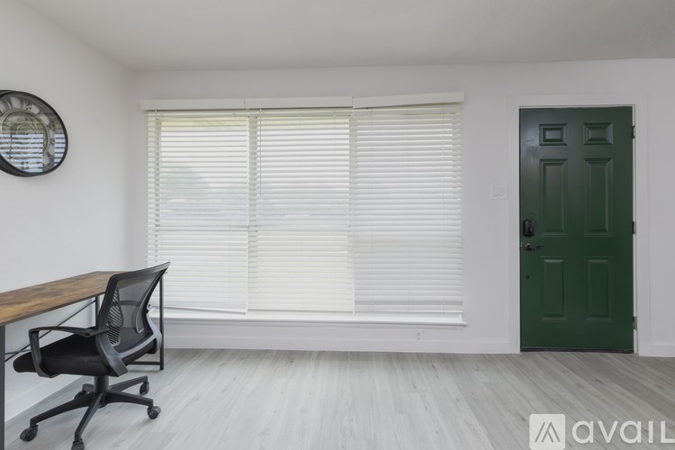 A room with a green door, a wooden table, and a black chair.