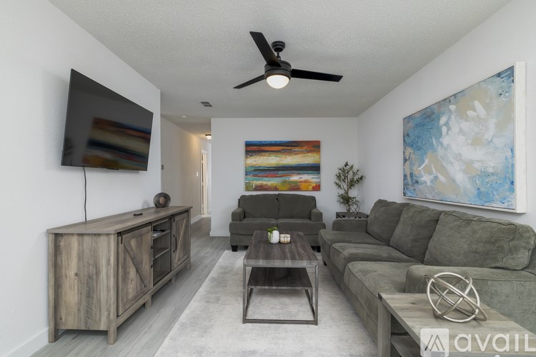 A living room with a grey couch, a wooden cabinet, and a painting on the wall.