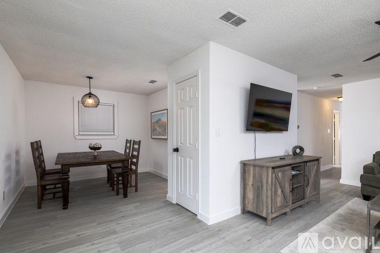 A living room with a wooden table and chairs, a television, and a cabinet.