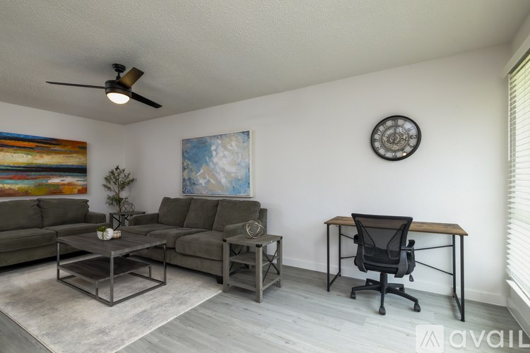 A living room with a grey couch, a coffee table, a chair, and a painting on the wall.