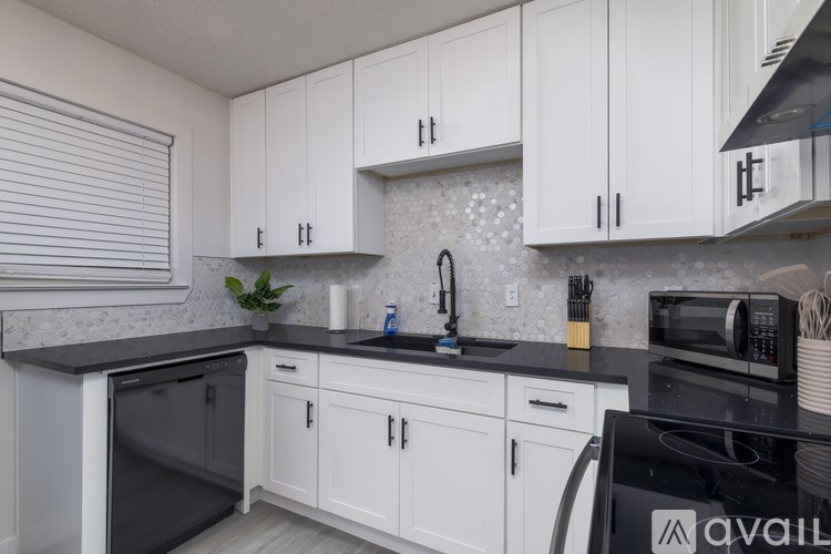A kitchen with white cabinets and black countertops.