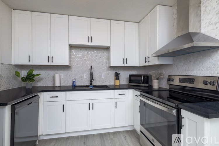 A kitchen with white cabinets and black countertops.