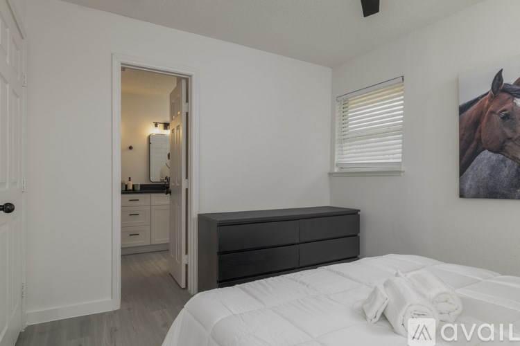 A bedroom with a large bed, a dresser, and a painting of a horse on the wall.