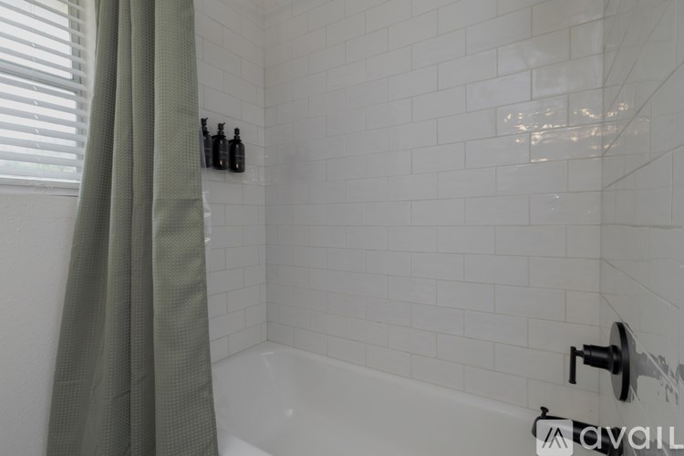 A white tiled bathroom with a green curtain.