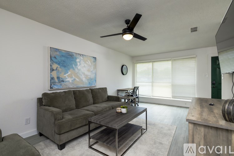 A living room with a grey couch, a coffee table, and a painting on the wall.