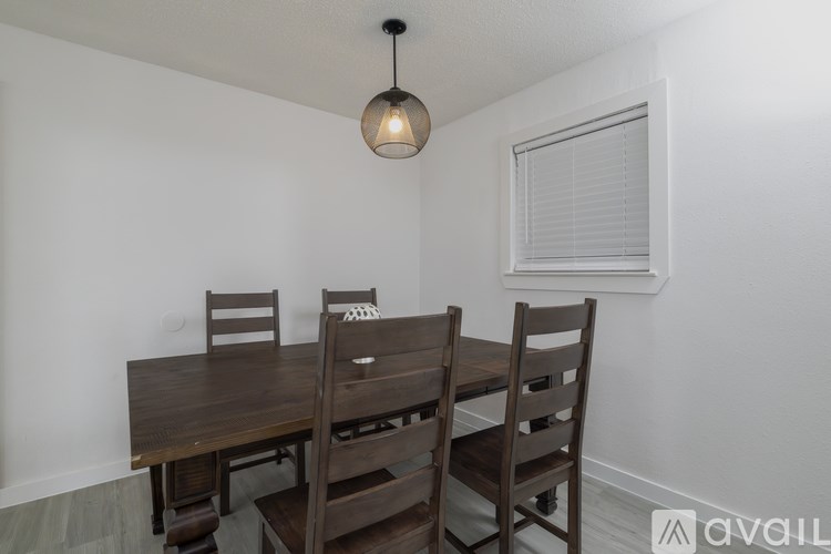 A wooden dining table with four chairs and a pendant light hanging above it.