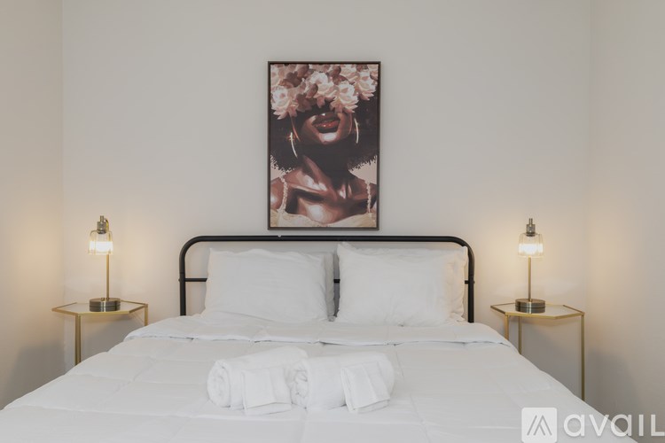 A bed with white bedding and a picture above it.