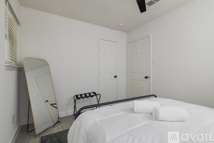 A bedroom with a bed, chair, and ironing board.
