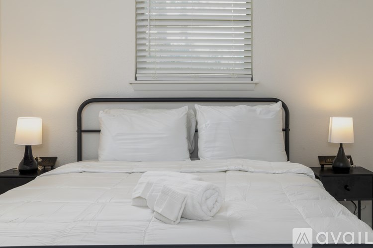 A neatly made bed with white bedding and two lamps on either side.
