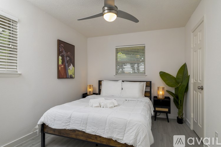 A bedroom with a bed, a ceiling fan, and a painting on the wall.