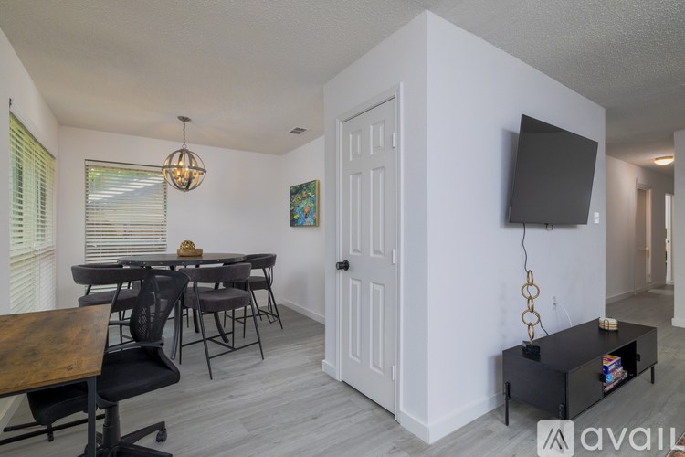 A room with a wooden table and chairs, a television, and a cabinet.