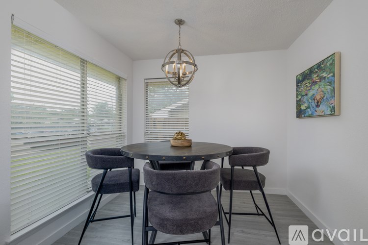 A dining room with a round table and grey chairs.