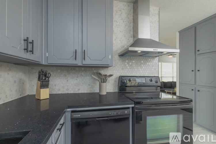 A kitchen with a black countertop and a stove with a pot on it.