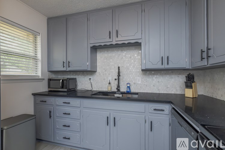 A kitchen with grey cabinets and a black countertop.