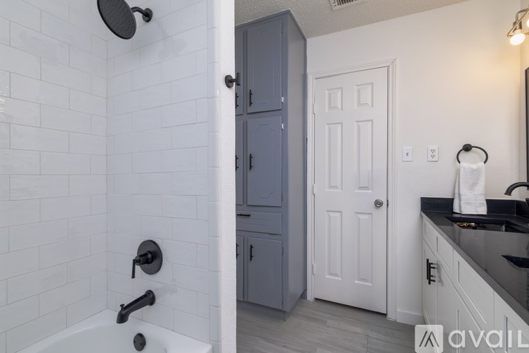 A bathroom with a white tiled shower and a white door.