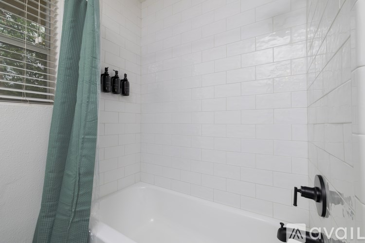 A white tiled bathroom with a green shower curtain.