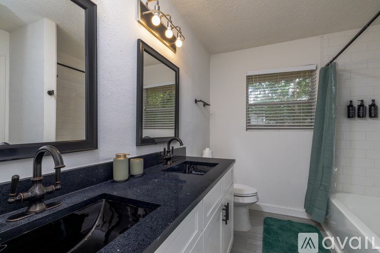 A bathroom with a black countertop and a green rug.