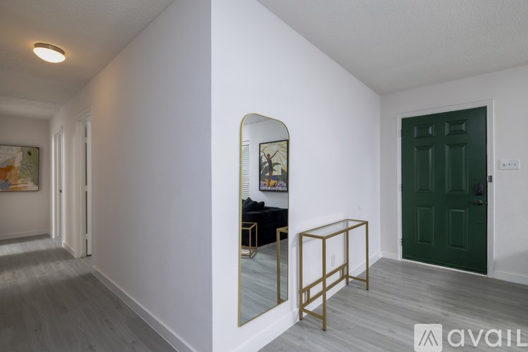 A hallway with a mirror and a green door.