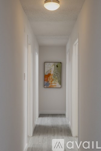 A long hallway with a painting on the wall and a light on the ceiling.