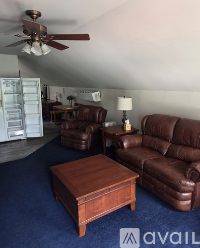 A living room with brown leather furniture and a ceiling fan.