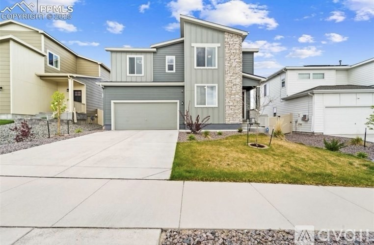 A house with a grey garage door is surrounded by other houses.