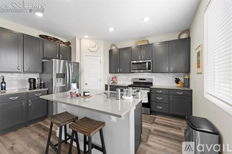 A modern kitchen with dark grey cabinets and a white island.
