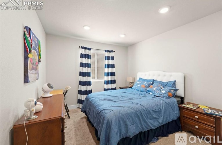 A bedroom with a bed, nightstand, and window with striped curtains.