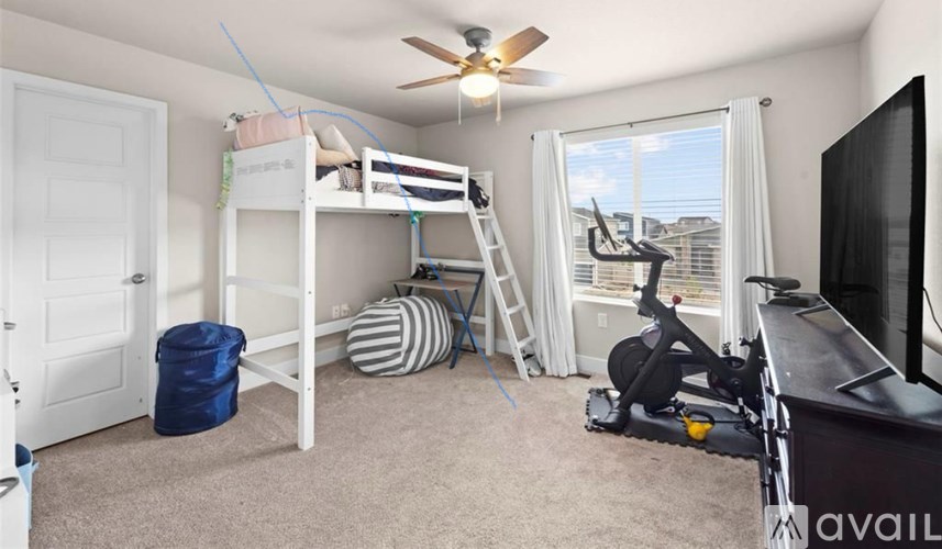 A room with a bunk bed, exercise bike, and a window overlooking the city.