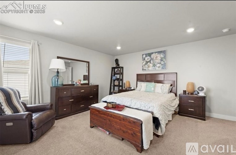 A bedroom with a large bed, a chair, and a nightstand.
