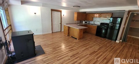 A kitchen with wooden floors and a black fridge.
