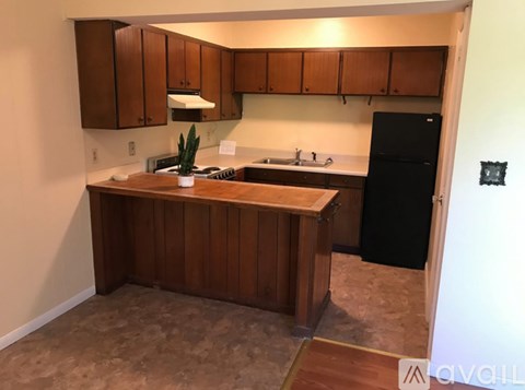 A kitchen with wooden cabinets and a black refrigerator.