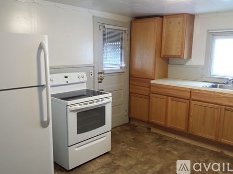 A kitchen with a white fridge, white oven, and wooden cabinets.