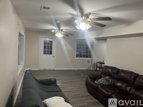 A living room with a brown leather couch and a ceiling fan.
