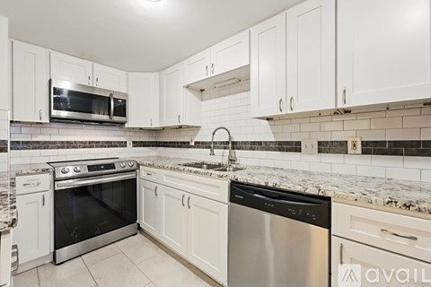 A kitchen with white cabinets and a black dishwasher.