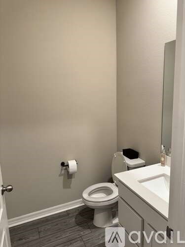 A bathroom with a toilet, sink, and mirror.