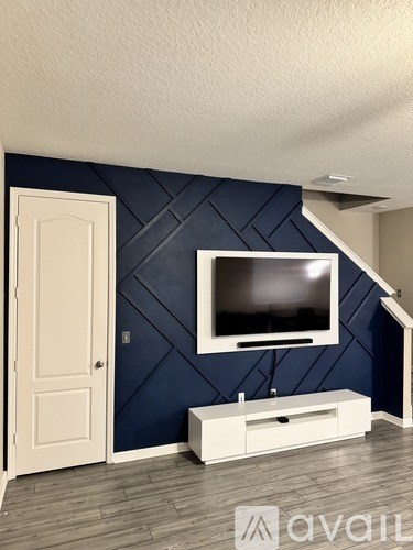 A white door is on the left side of a room with a blue wall and a television mounted on it.