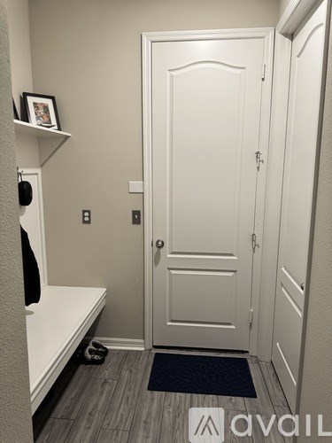 A white door is in a hallway with a black mat on the floor.