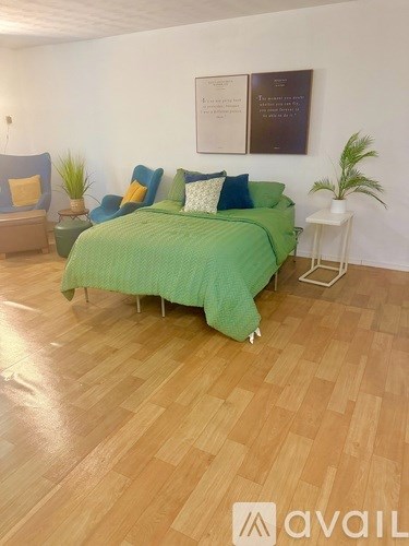 A bedroom with a green bed and wooden flooring.