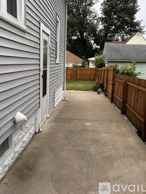 A grey house with a wooden fence and a concrete walkway.